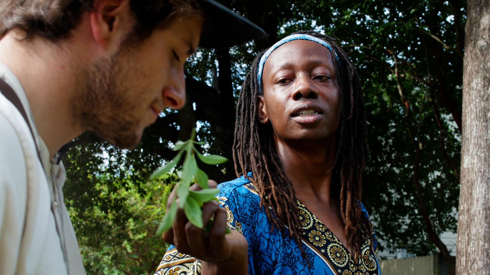 A New Orleans herbalist offering a sprig of herbs to a visitor